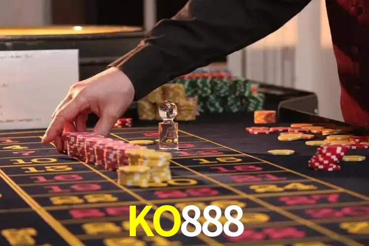 Escena dinámica inspirada en casino con iluminación KO888, cartas, fichas e íconos de juegos digitales en un espacio moderno de juegos.